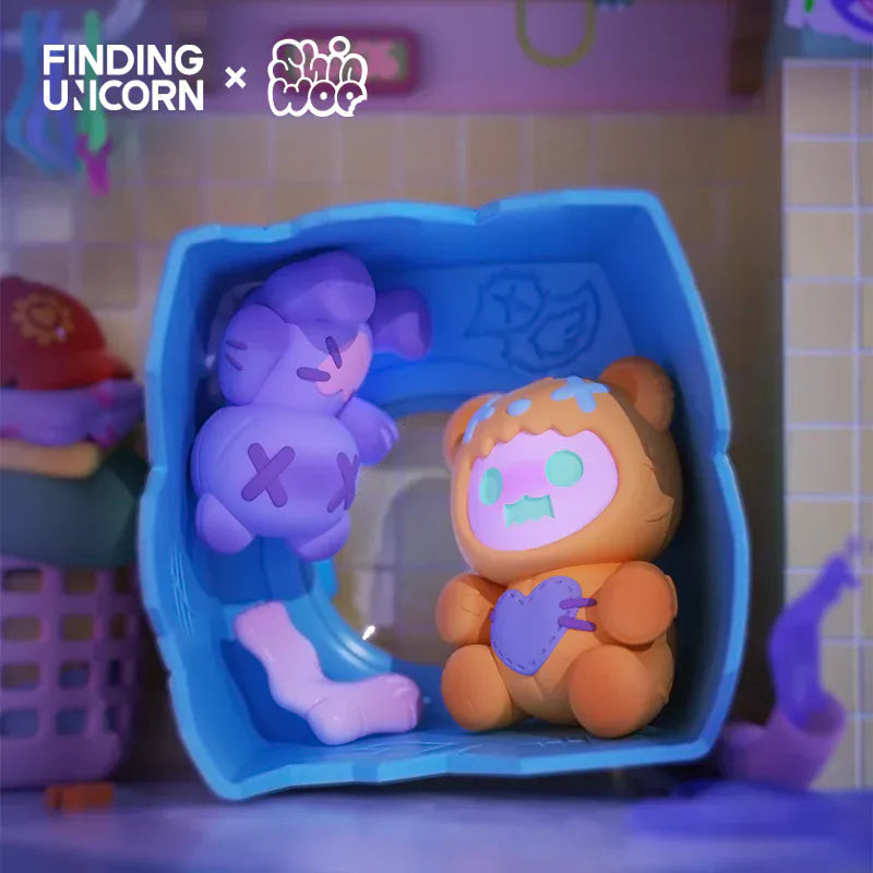 A cute figurine of a ghost wearing a dead bear skin in a blue box with a figurine of a bear plush.