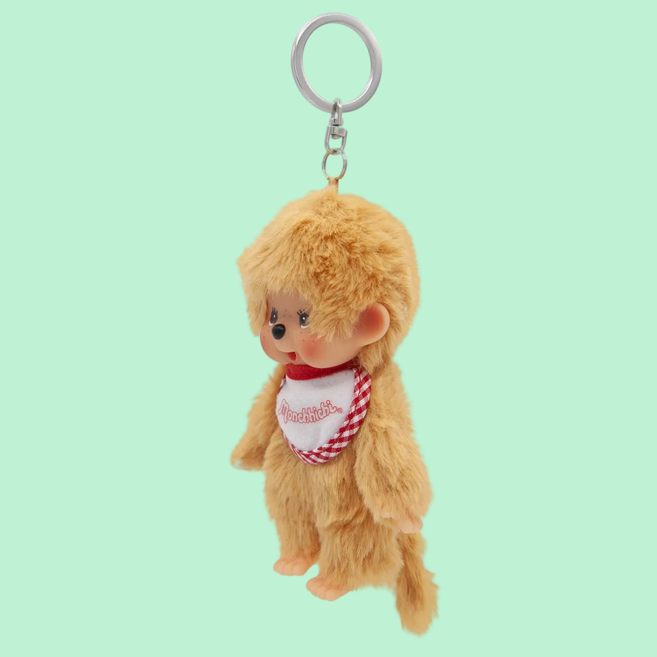 A beige Mochhichi monkey keychain wearing a bib that says Monchhichi.