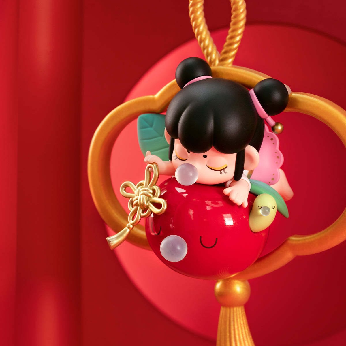 A figure of a little girl laying on top of a bright red apple with a worm coming out. All three are blowing gum bubbles.