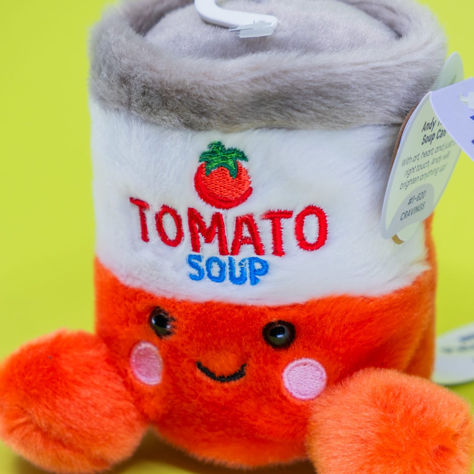 A cute plush of a can of tomato soup. The can has a smiley face on the front.