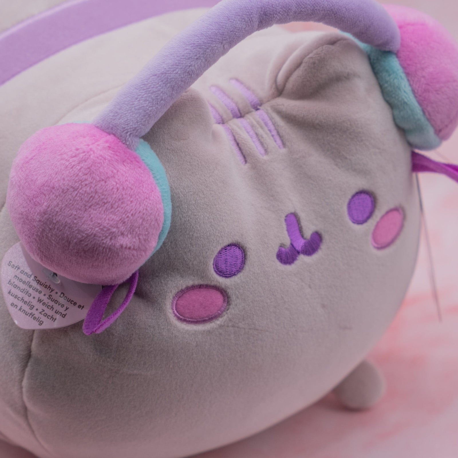 A large pink cat plush wearing pink headphones.