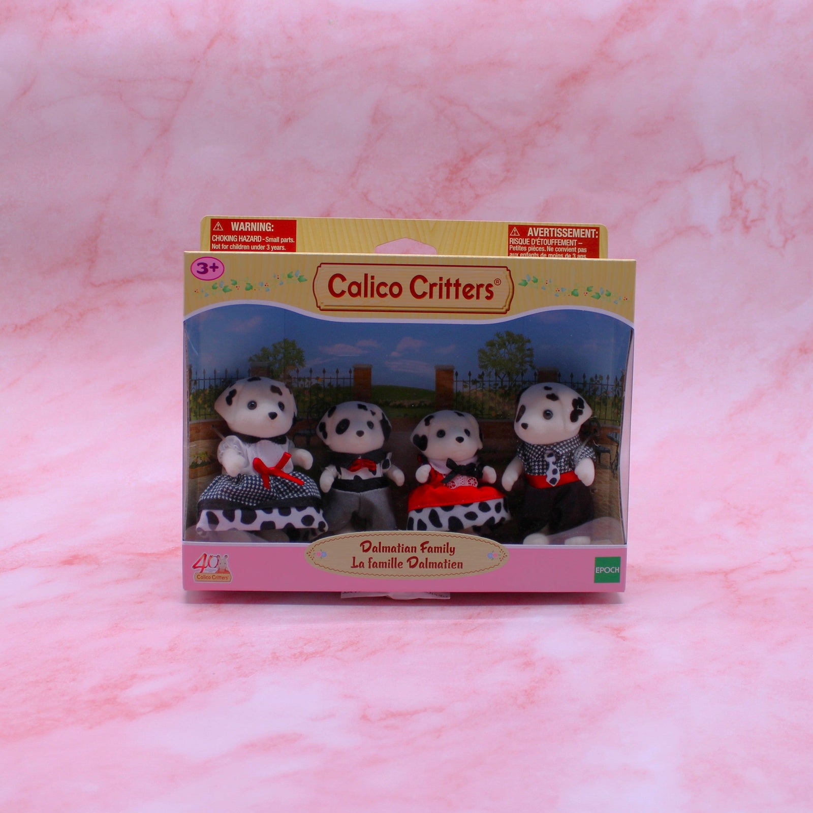 Four Dalmatian figures in a box. On the left is the mother in a black and white dress with a red bow. Then, the little boy is wearing gray pants and a spotted top with a red bow. Next to him is the sister in a red dress with a black bow and a spotted underskirt. Finally, the dad is rocking a black and white top with a red belt, black pants, and a spotted tie.