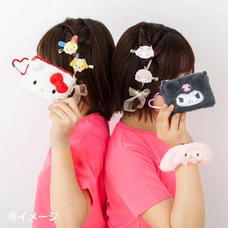 Two people holding up the Hello Kitty and Kuromi mini flat pouches