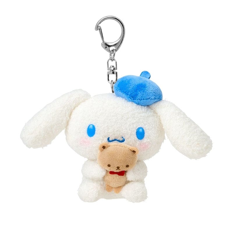Plush keychain with a Cinnamoroll, a white puppy character, holding a small bear, while wearing a blue beret