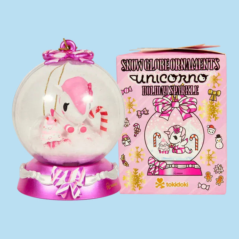 A Tokidoki ornament of a unicorn in a snow globe beside a pink blind box for various other Tokidoki snow globe ornaments.