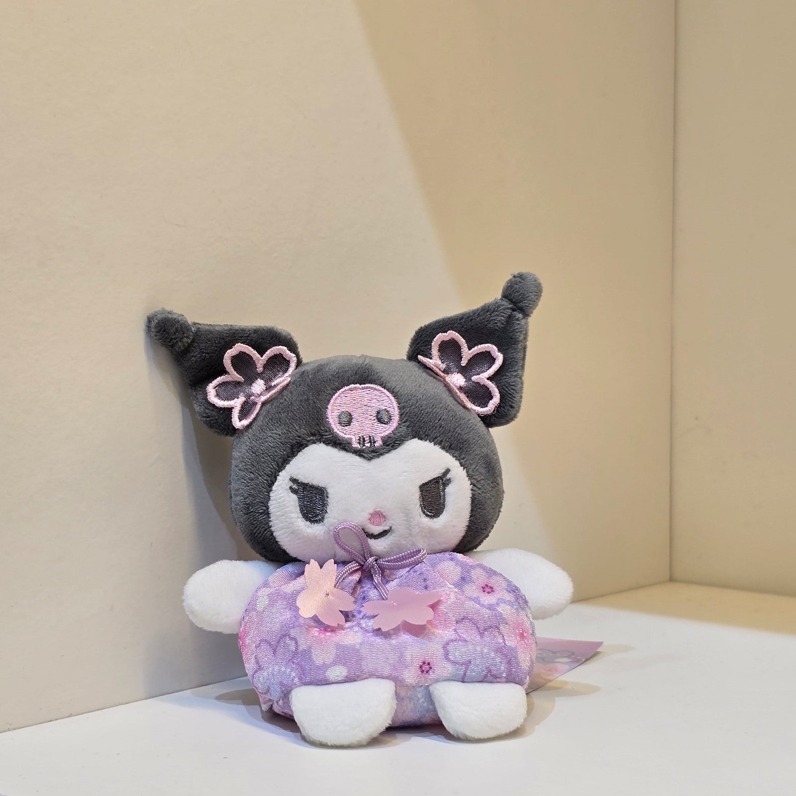 A cute Kuromi plush in a purple flower outfit.