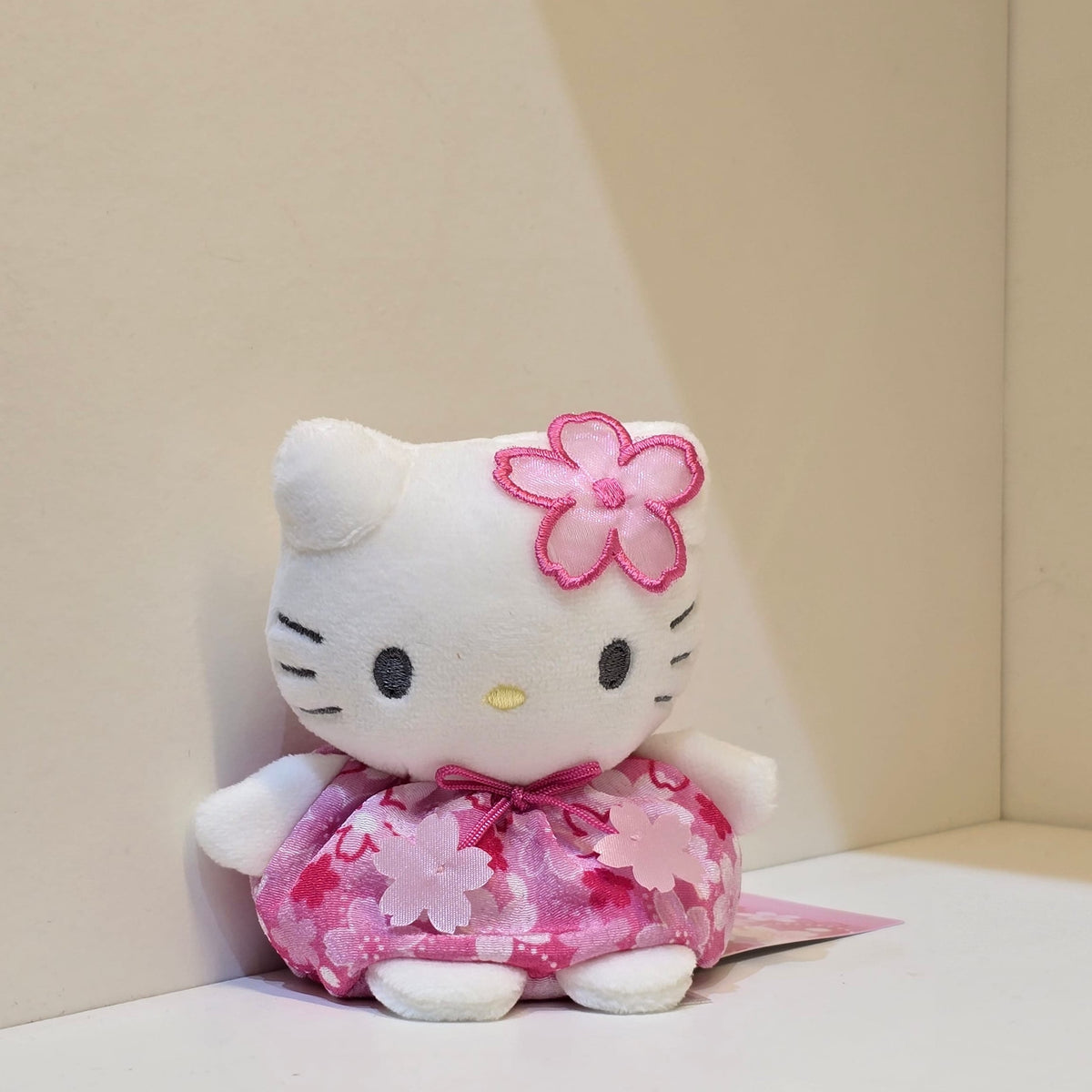 A cute plush of hello kitty in a pink flower outfit.