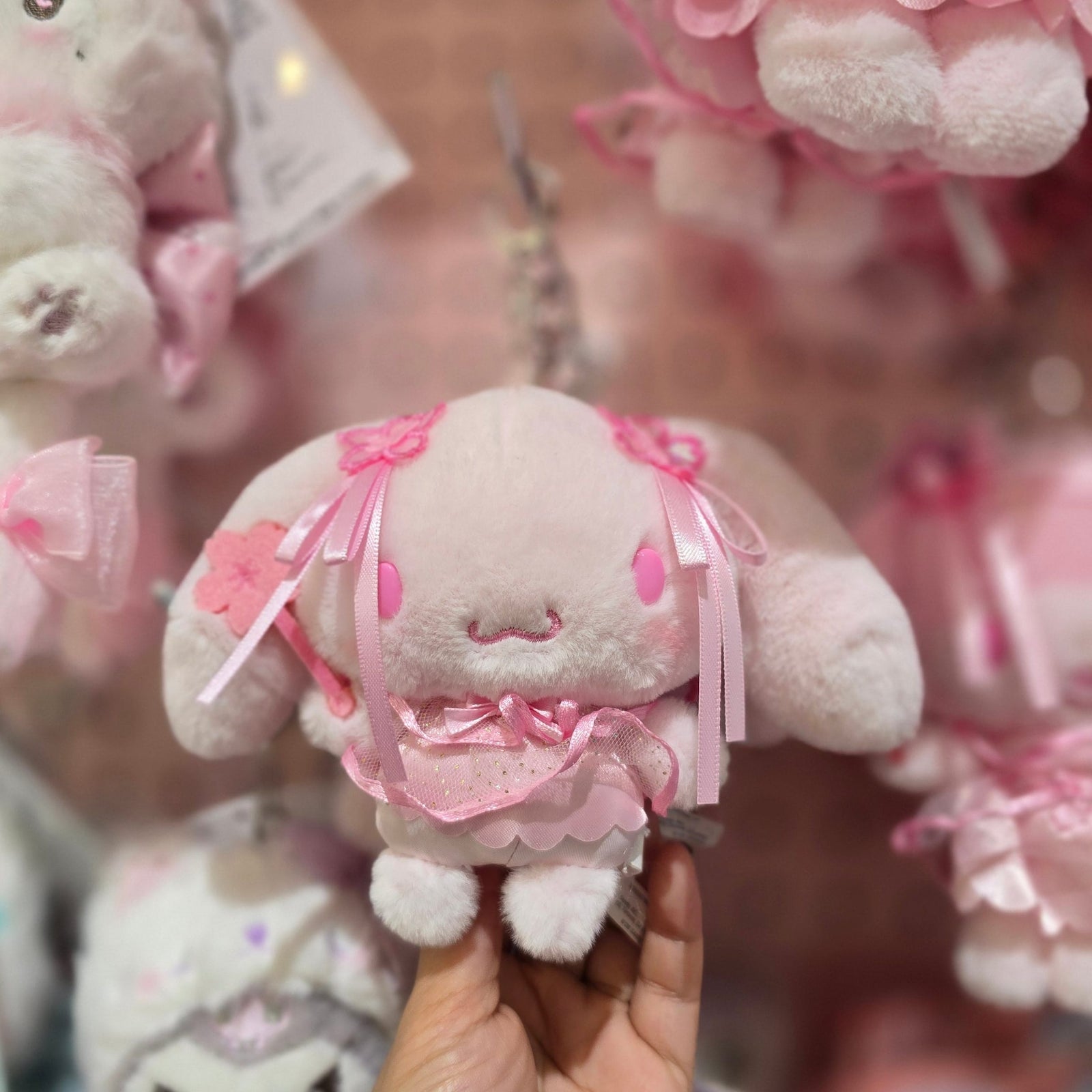 A pink Cinnamoroll plush key chain. He is holding a pink flower wand.