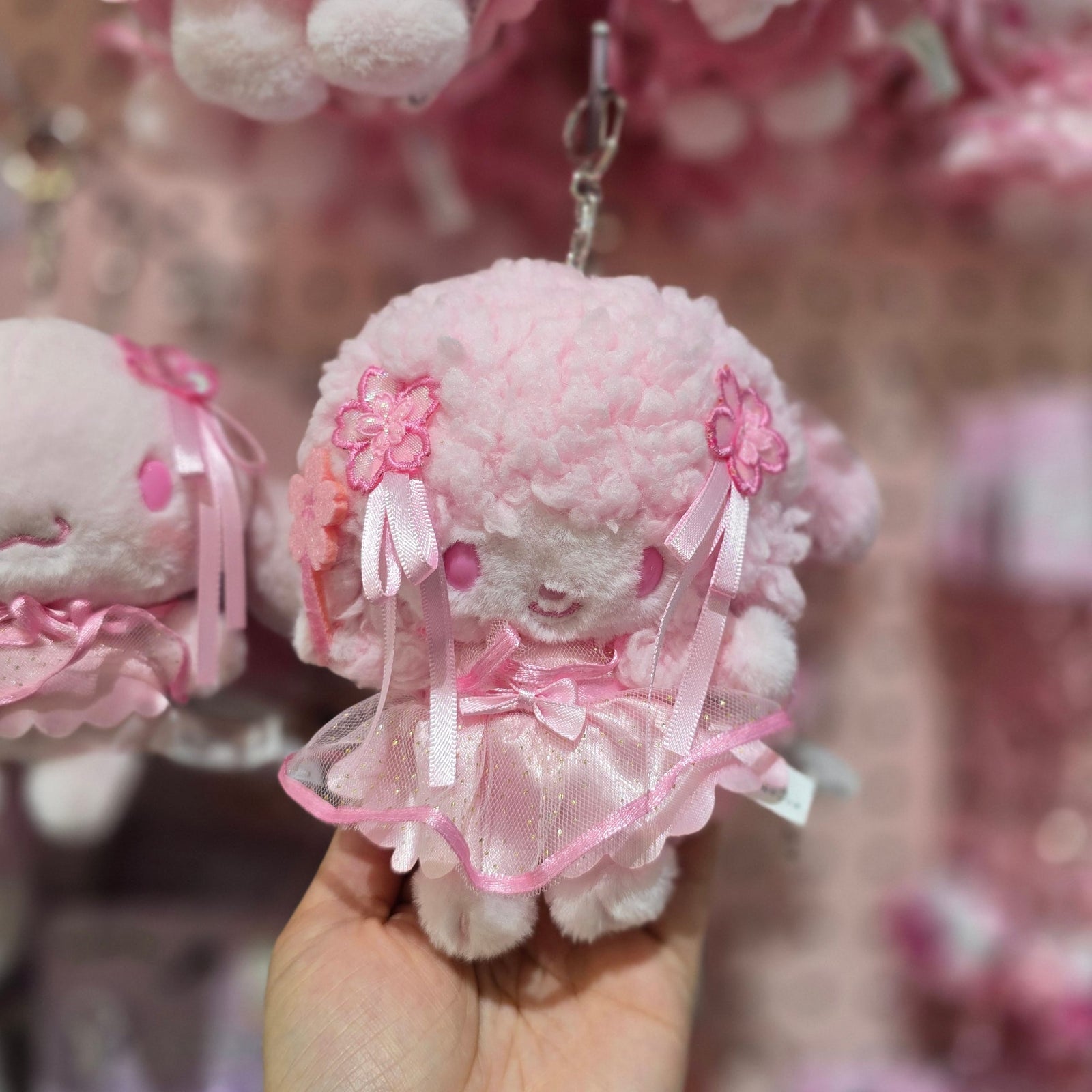 A cute pink plush keychain of a character with wooly pink harir.