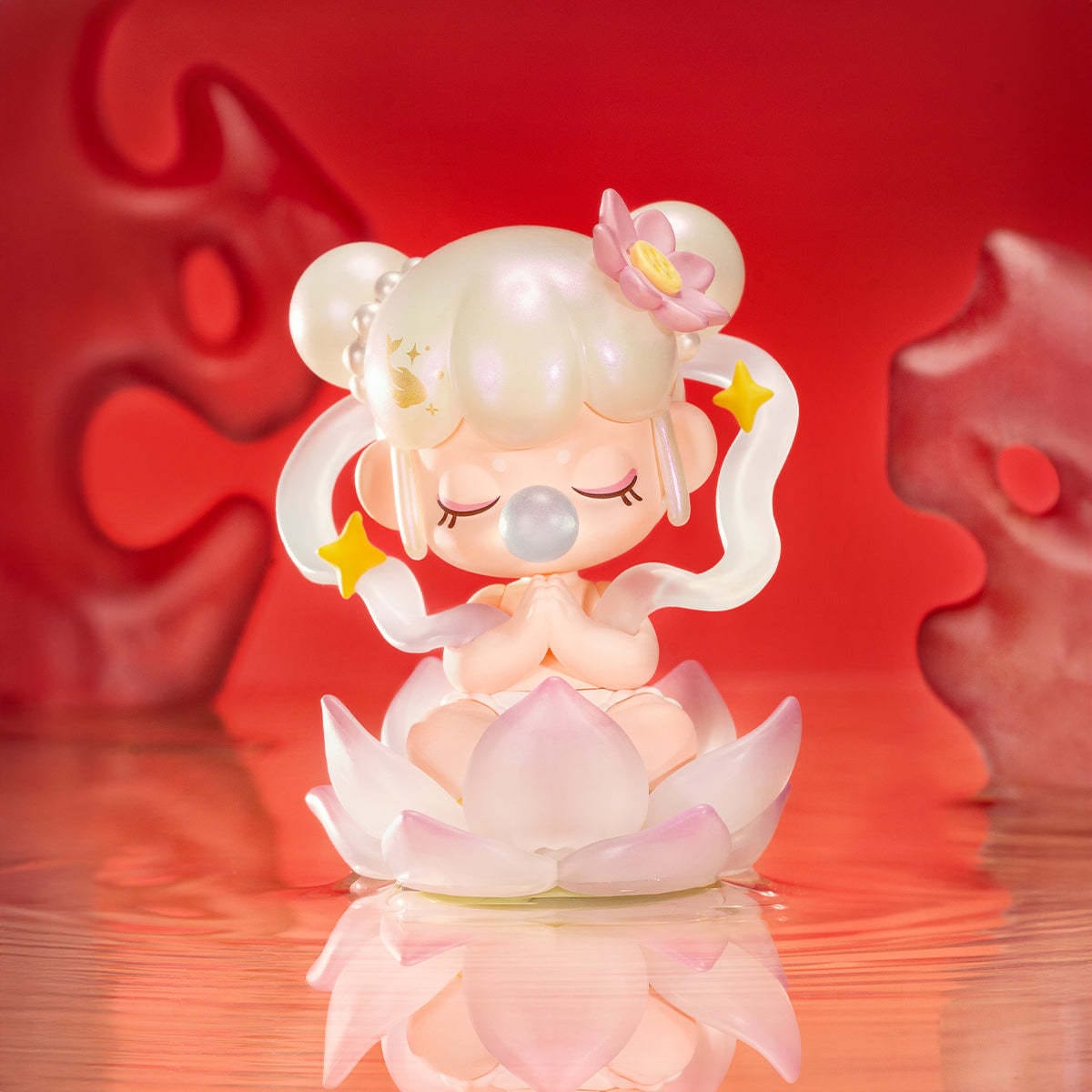 A figure of a little girl sitting in a lotus flower and praying. She is blowing a bubble.