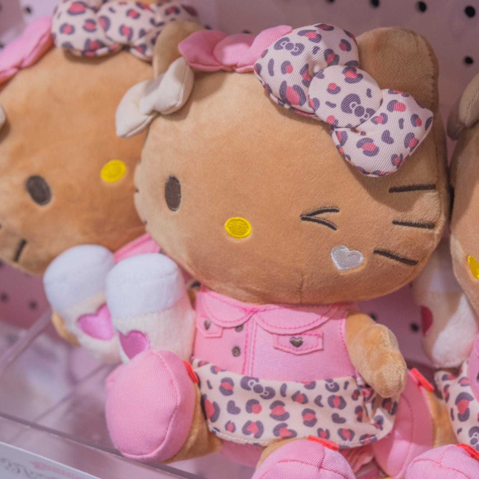 A cute, brown, Hello Kitty plush. She is wearing a pink outfit and holding a bottle of milk.