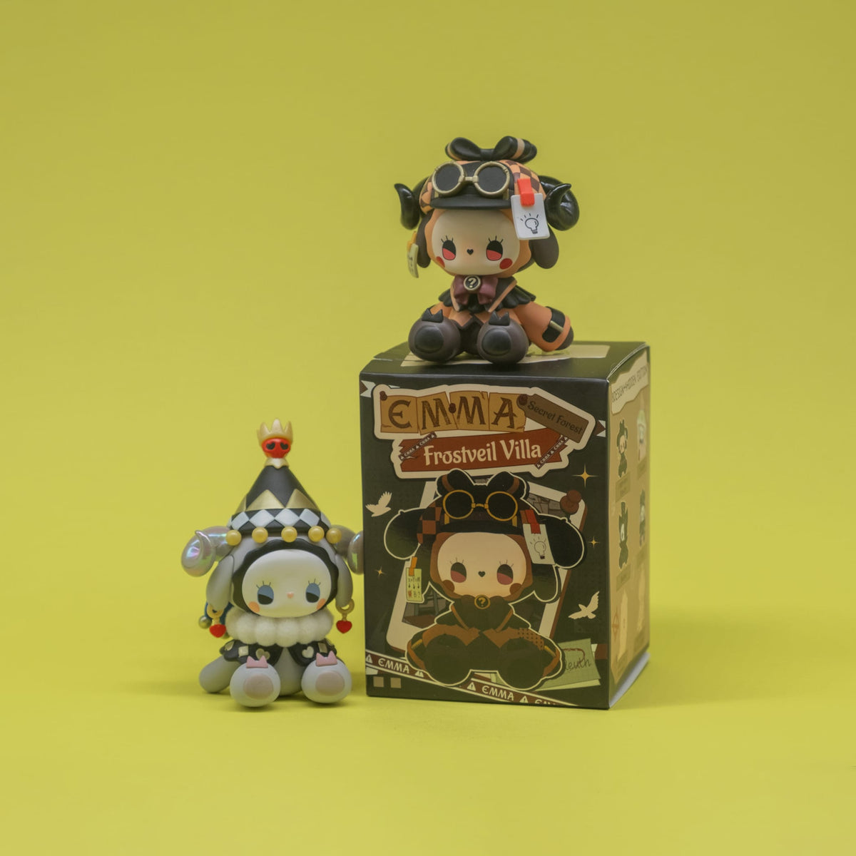 Two cute anthropomorphic goat figures. One is wearing a cute jester outfit while the other is in a steampunk outfit.