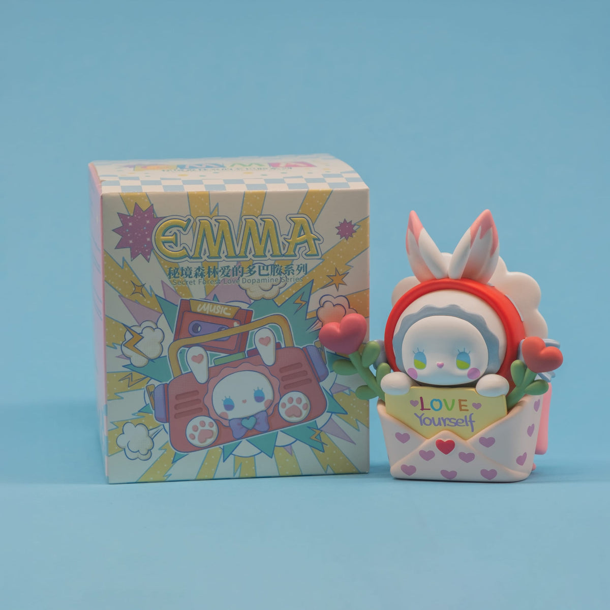 A figure of a little rabbit sitting in an envelope with heart shaped flowers and a note reading "love yourself".