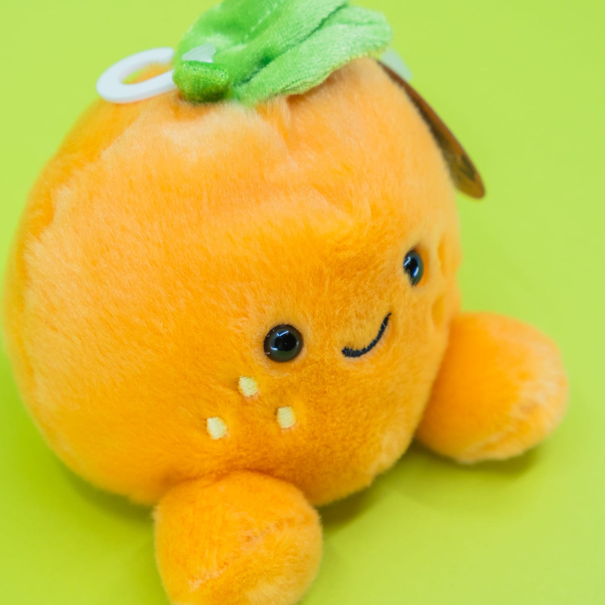 A cute plush of an orange. It has a smiley face on the front.