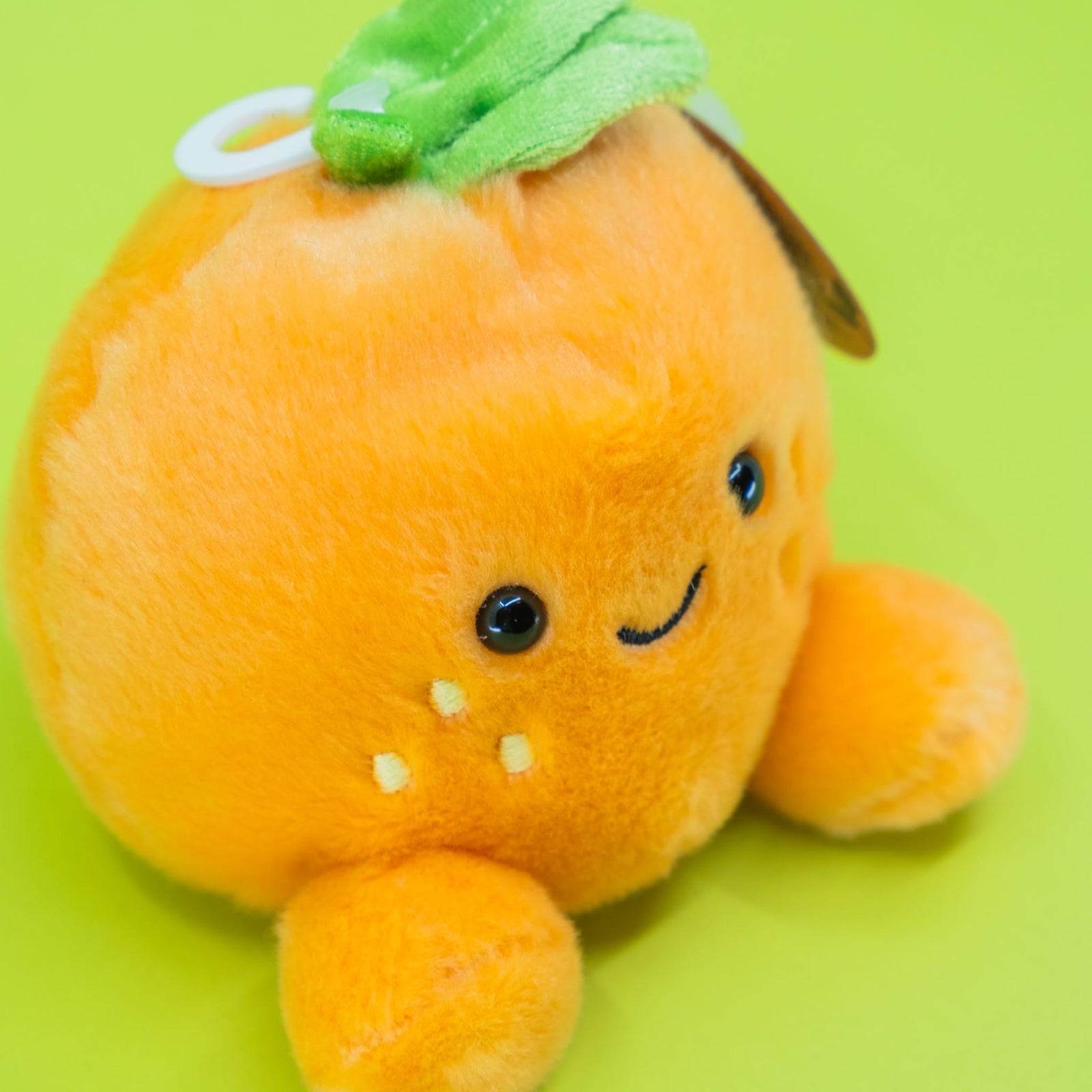 A cute plush of an orange. It has a smiley face on the front.