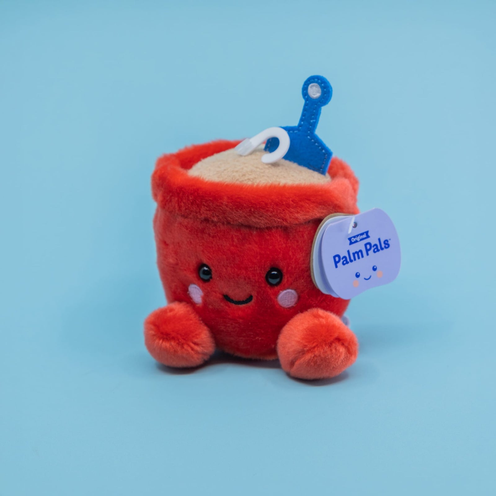 A cute red sand pail plush. It has a smiley face and little feet.