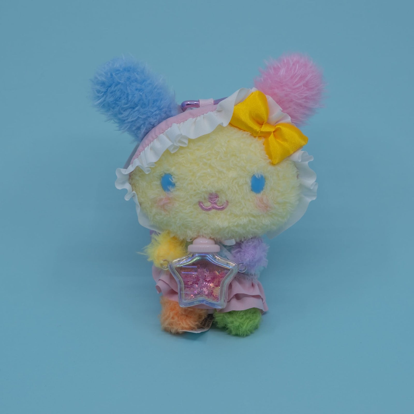 A colorful Usahana plush key chain. She is holding a small star shaped bottle.