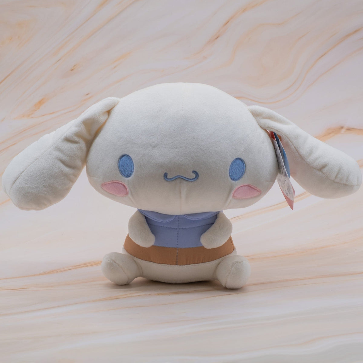 A plush of a rabbit with a large head. The rabbit is also wearing a blue shirt.