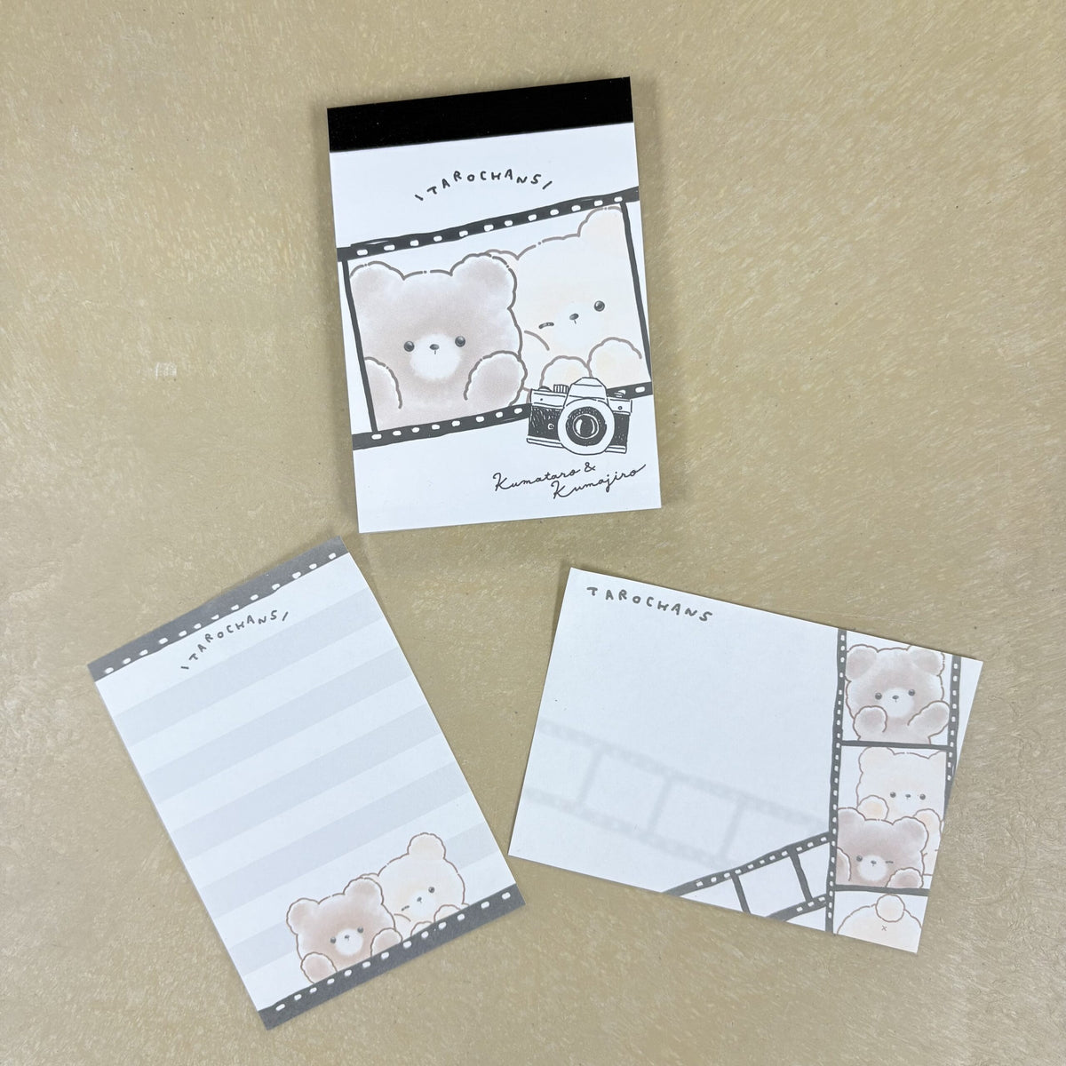 Several pages of a notepad showing illustrations of two cute bear characters with an older camera.