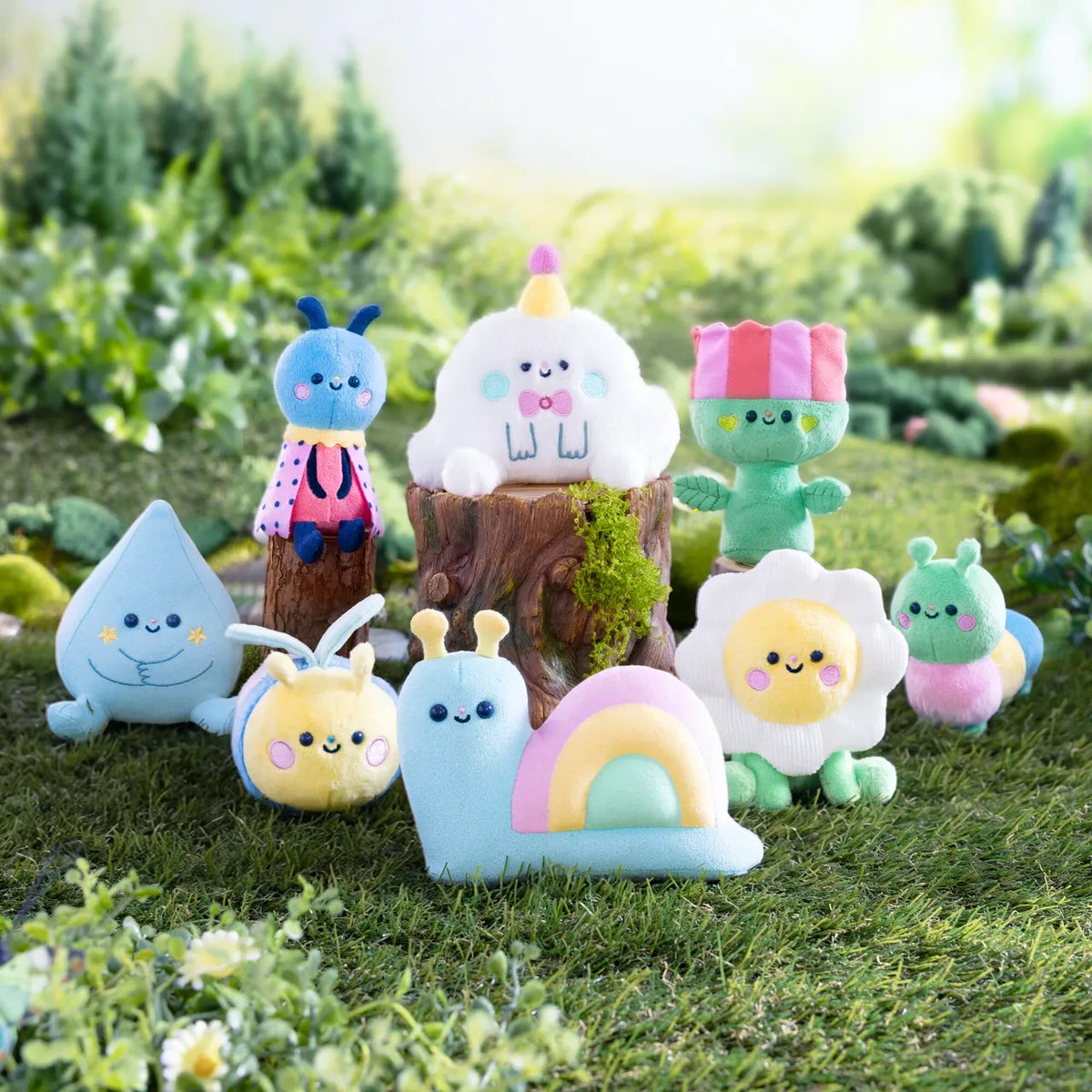 A collection of various cute meadow themed plushies sat in a field. There is a snail, a raindrop, a ladybug, and various others.