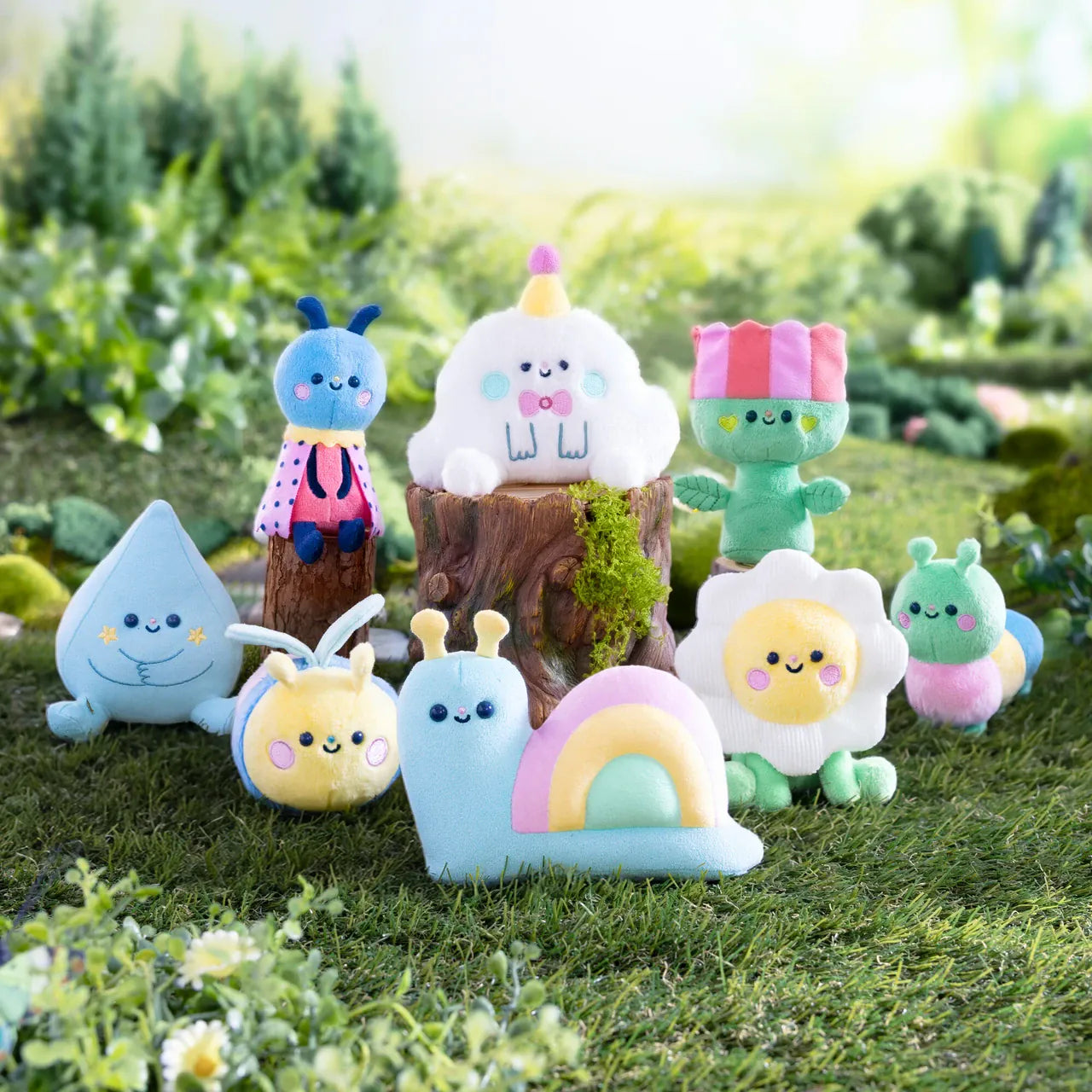 A collection of various cute meadow themed plushies sat in a field. There is a snail, a raindrop, a ladybug, and various others.