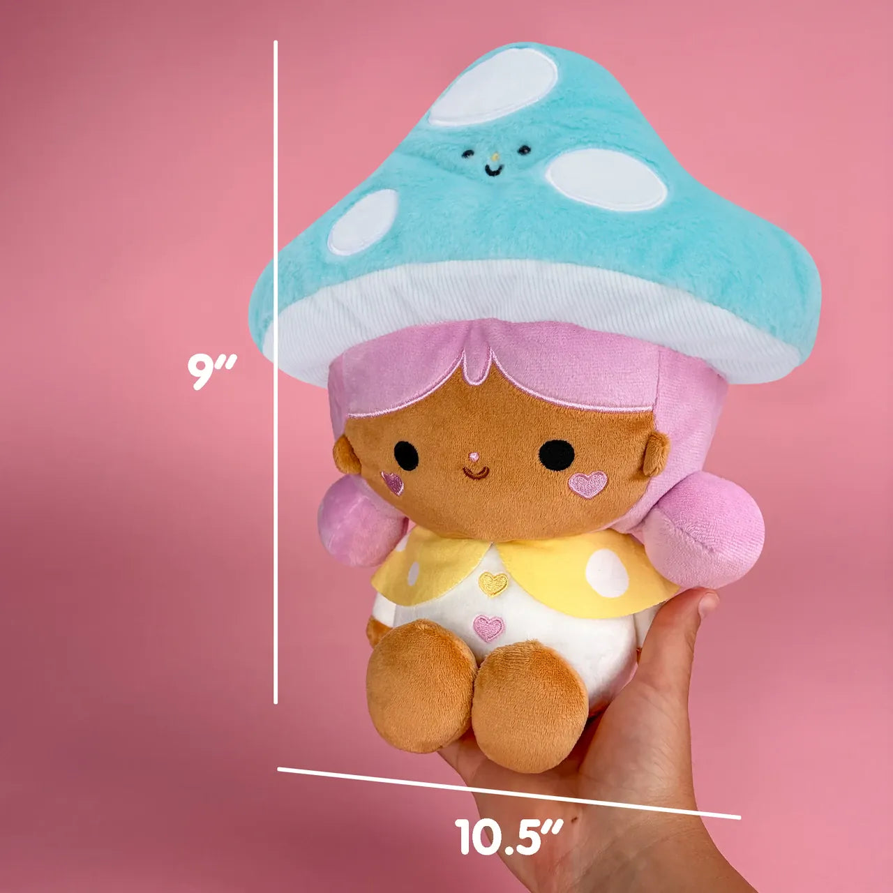 A cute plush of a girl wearing a bright blue mushroom hat. There are measurements showing she is 9 inches tall, and 10.5 inches wide.