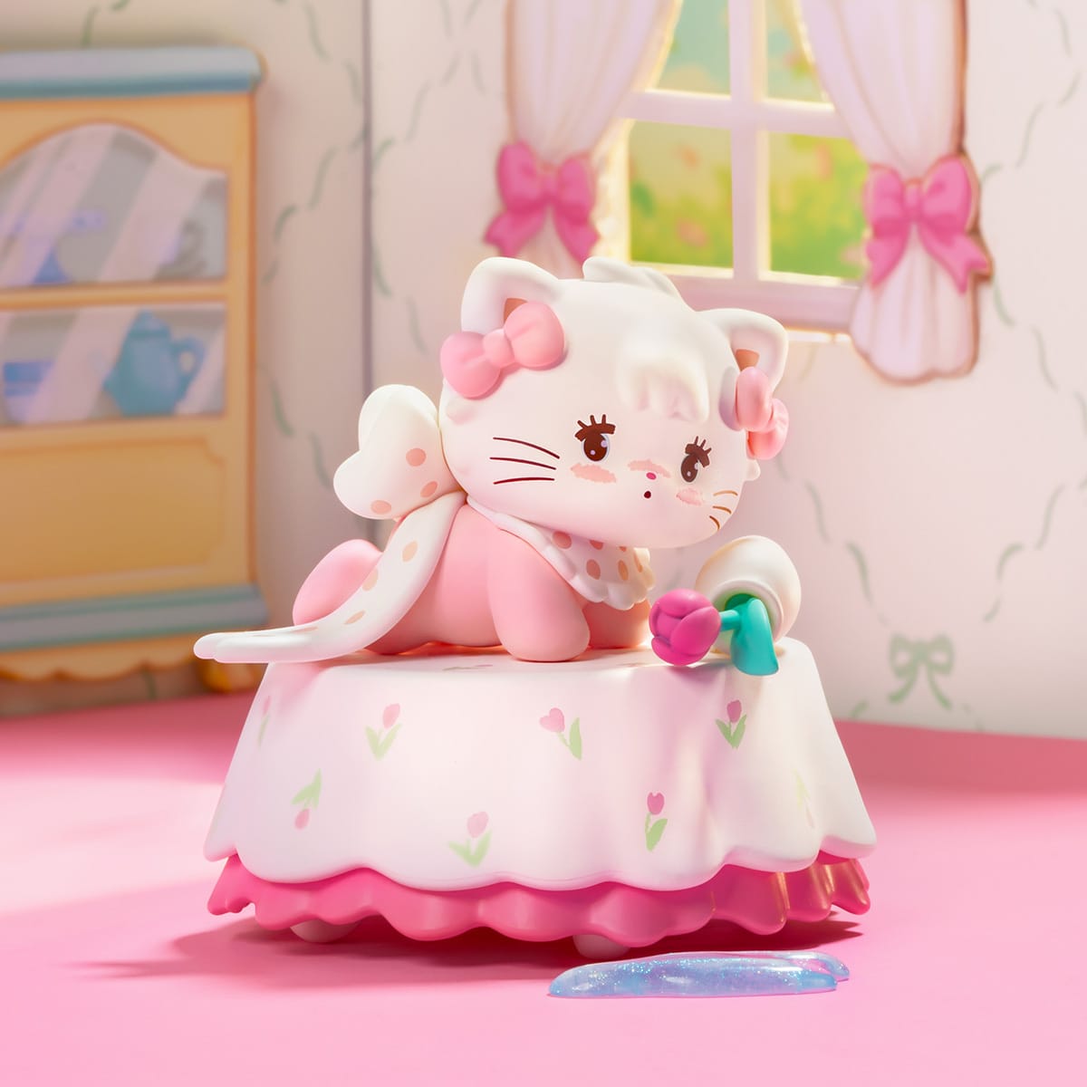 A figure of an anthropomorphic cat laying on a table. There is a knocked over vase on the table and the cat is pink.