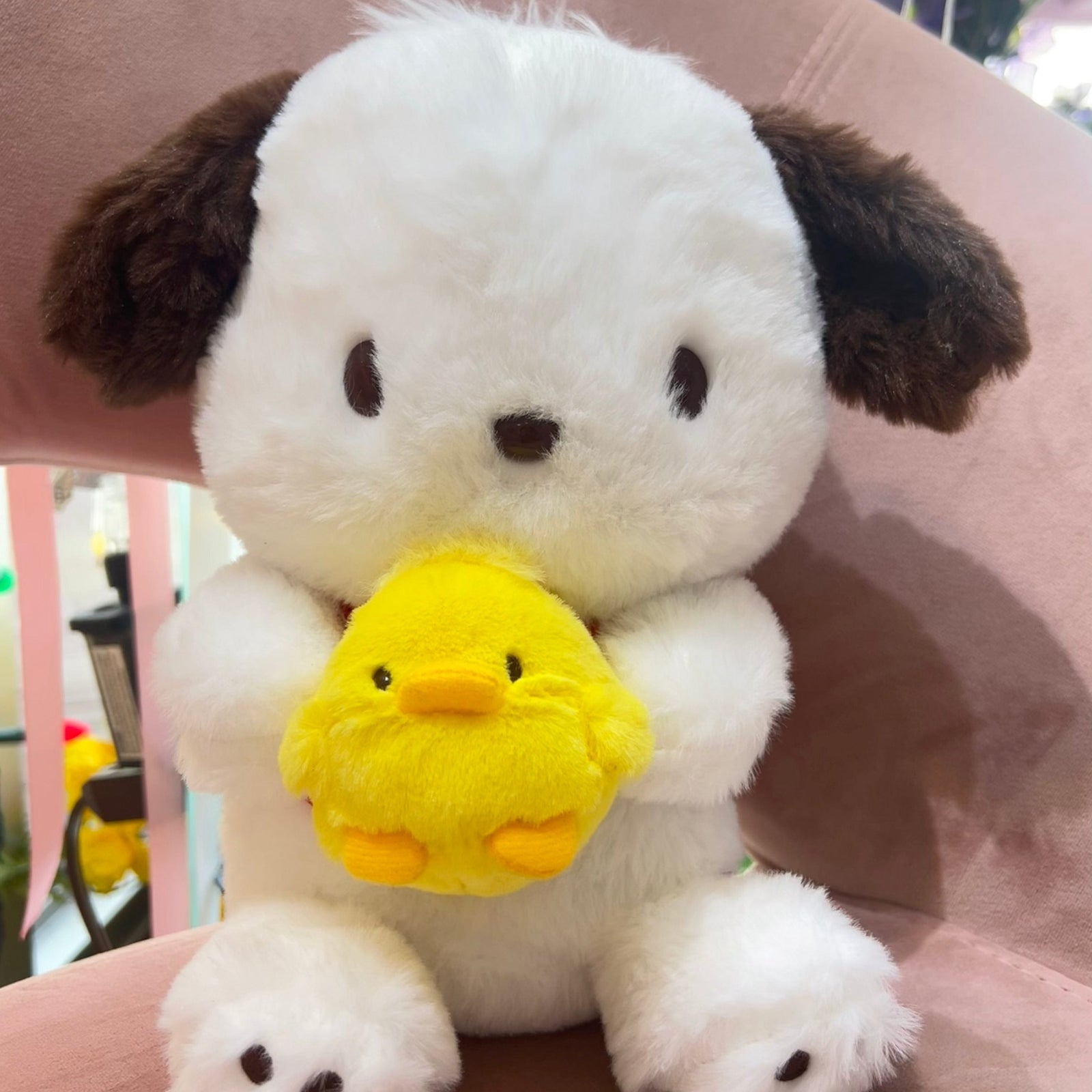 A Pochacco plush. He is holding a very round baby chick.