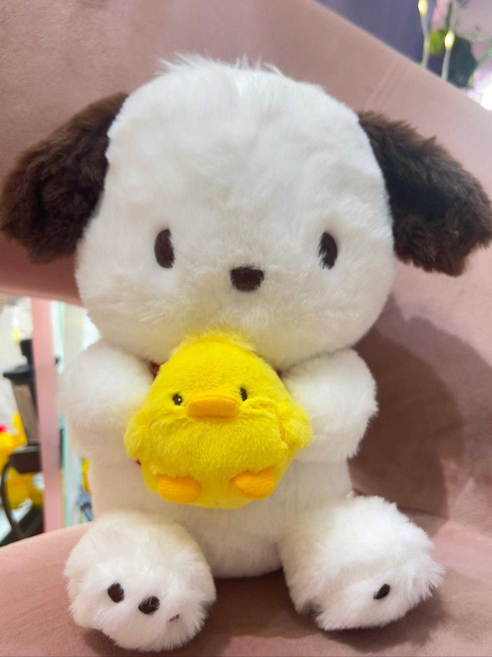 A Pochacco plush. He is holding a very round baby chick.