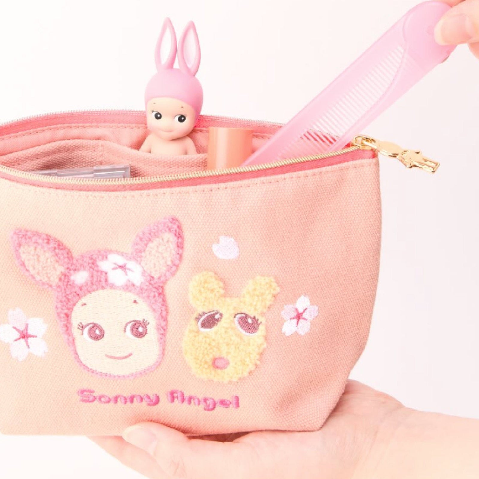 Pinkish pencil case with text on the front that says Sonny Angel. There is an image of a cute baby wearing bunny ears and a small animal stitched in to the front.