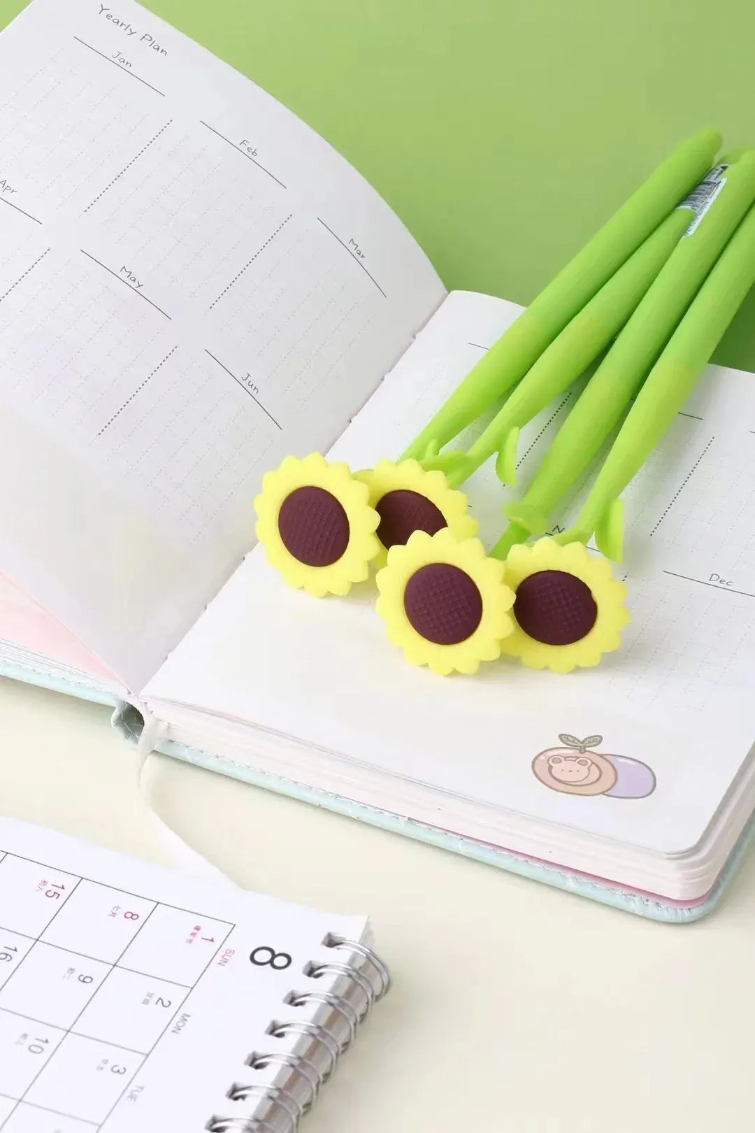 A group of pens designed to look like sunflowers resting on a notebook.