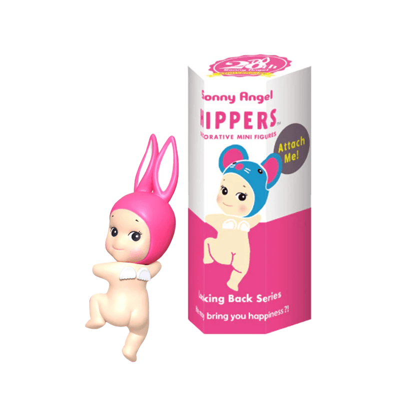 A Sonny Angel Hipper wearing a pink rabbit hood and looking over its shoulder next to the box the Hipper comes in. 