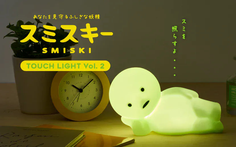 A glowing figurine of a green man resting on his side. Text overlay says Smiski and Touch Light Vol.2