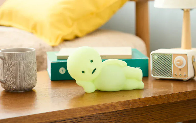 Figurine of a green man resting lazily on his side on top of a desk.