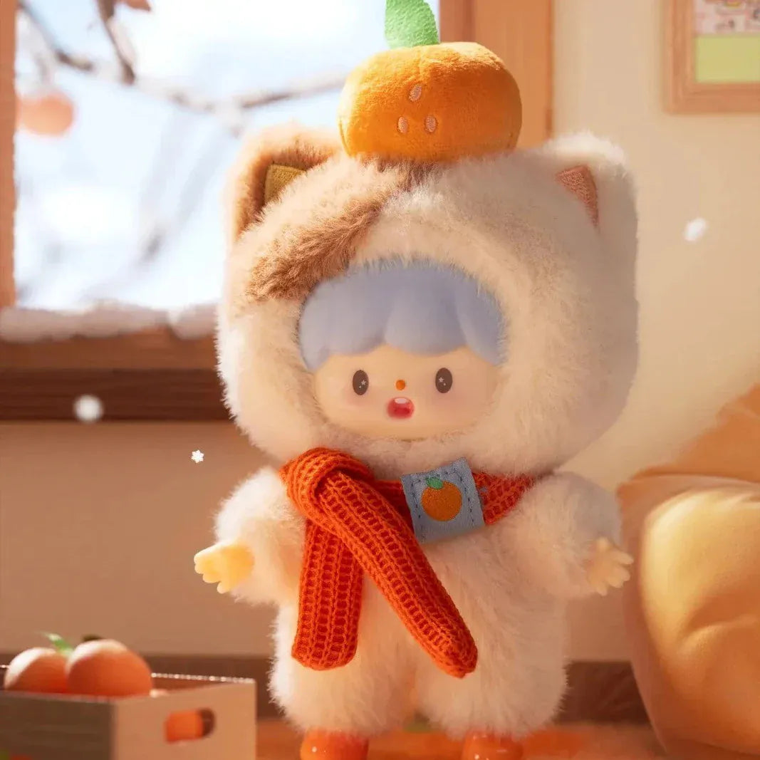 A figurine of a child wearing a fluffy cat costume with a small pumpkin on their head. They are also wearing an orange scarf.