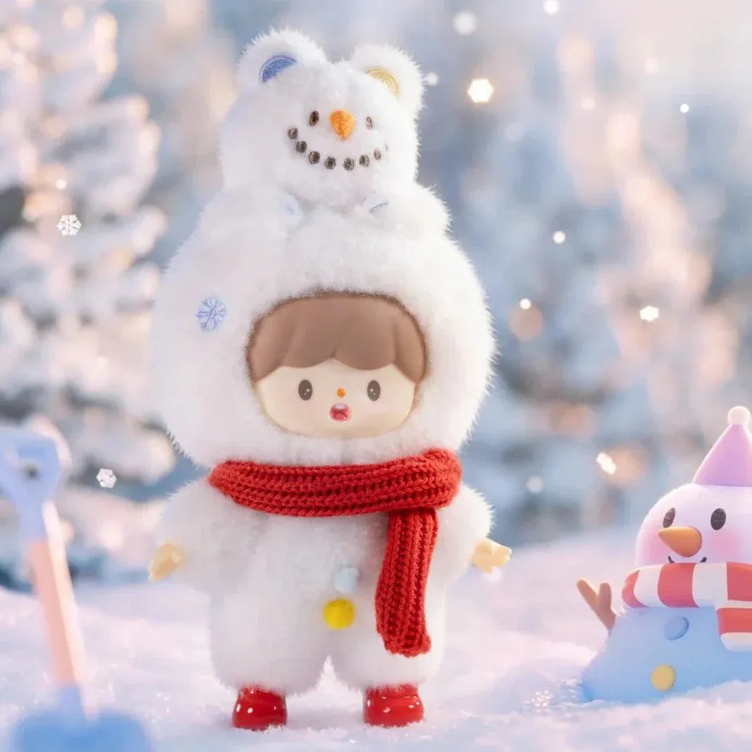 A figurine of a child wearing a fluffy snowman outfit with a snowman bear on their head. The figurine is standing in a snowy forest.