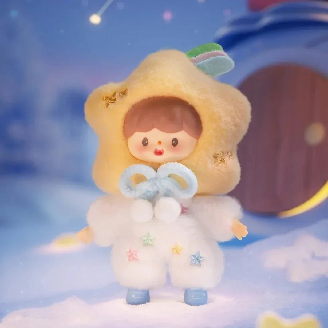 A figurine of a child in a fluffy star hat. Their shirt is white with a colorful star pattern.